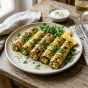 Grilled zucchini rolls stuffed with herb and cheese filling on a plate with salad greens and lemon wedges